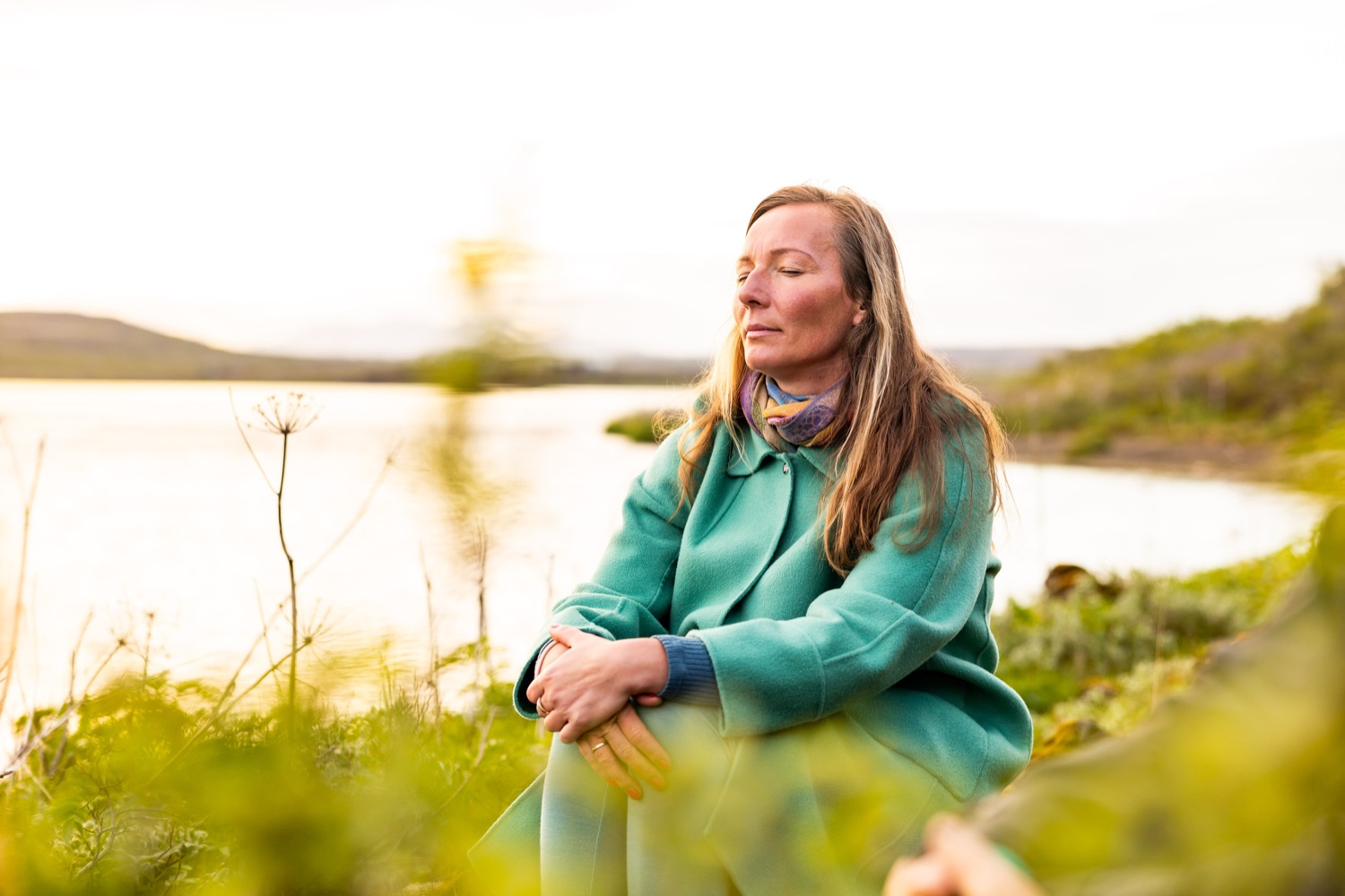 Dr. Julia König sitzt am Ufer eines Flusses in Island